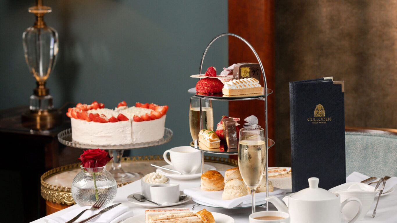 Elegant afternoon tea setting with gourmet cakes, scones, and champagne at a luxurious hotel, exuding warmth and sophistication.