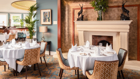 Elegant hotel dining room with cosy fireplace, luxurious seating, and artful decor, perfect for a sophisticated dining experience.