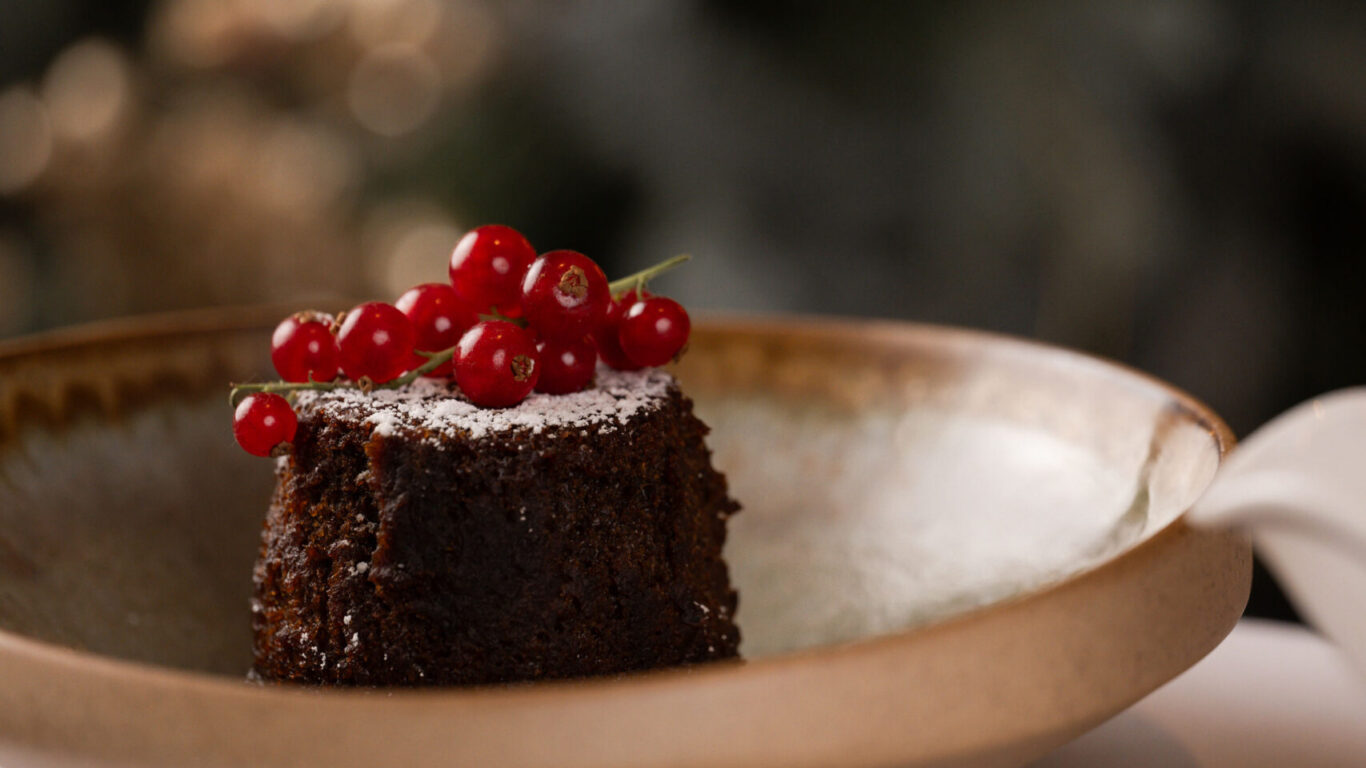 Indulge in a rich Christmas pudding topped with red berries, served with ice cream at our elegant hotel restaurant.