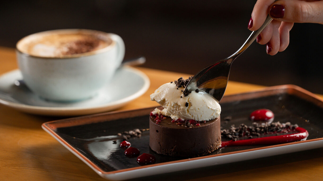 Indulge in gourmet chocolate dessert with rich cappuccino at our luxurious hotel restaurant, perfect for a relaxing stay.