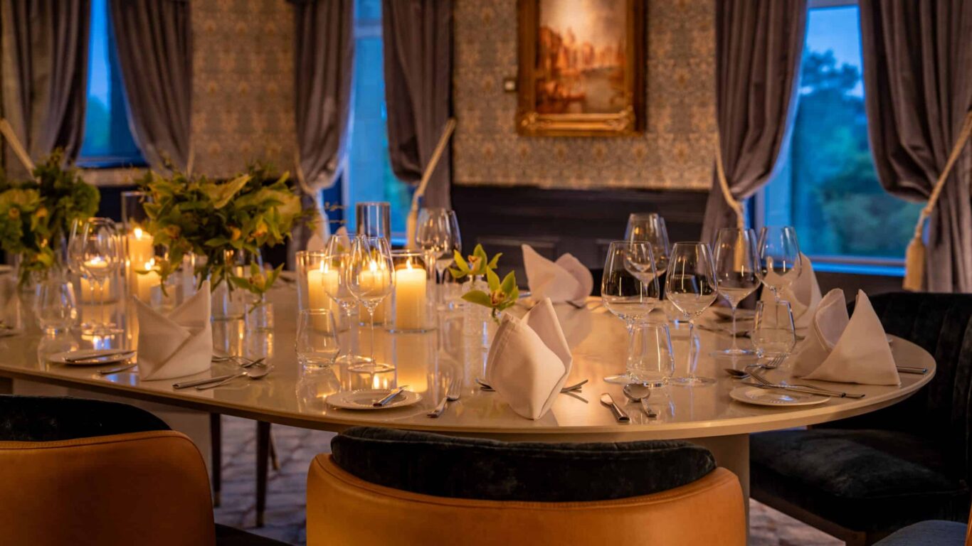 Elegant dining room with candlelit table, fine china, and plush seats, offering a sophisticated dining experience.