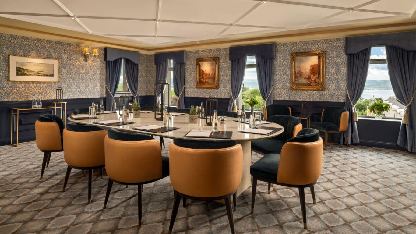 Elegant meeting room with sea view, luxurious chairs, rich decor, and natural light, offering a perfect venue for business events.
